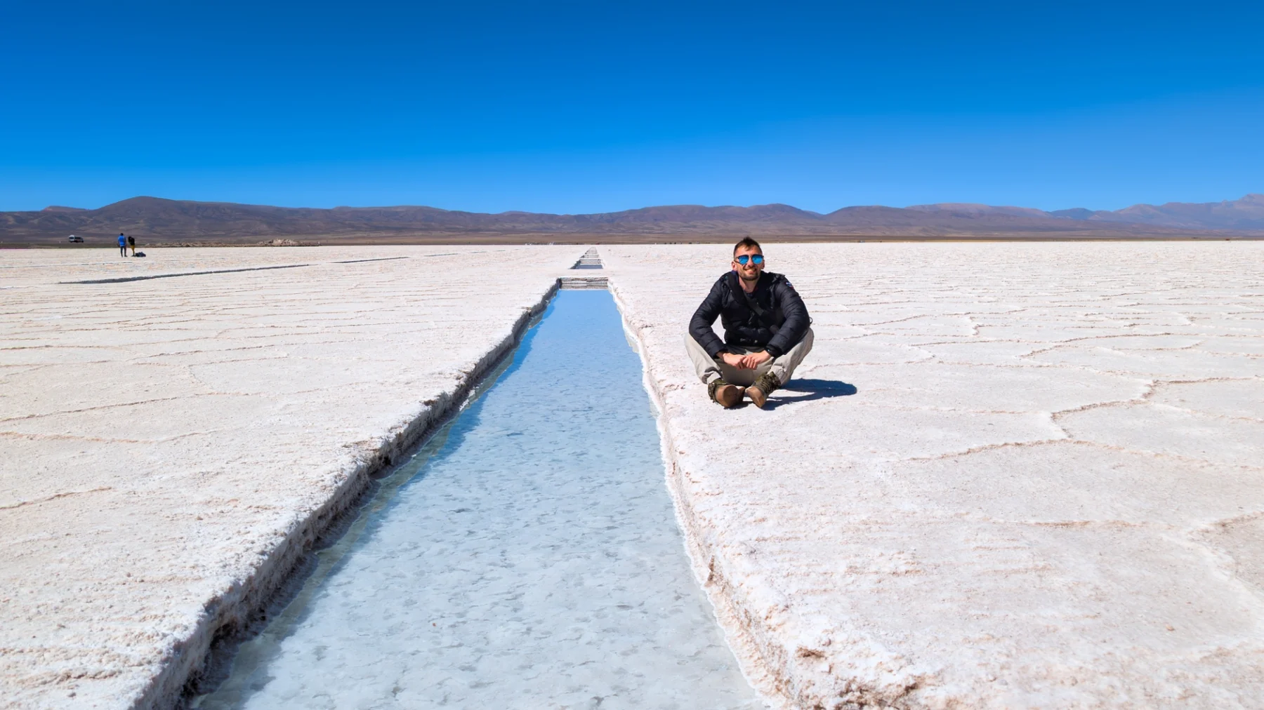 A lone figure crossing the vast white salt flats of Salinas Grandes