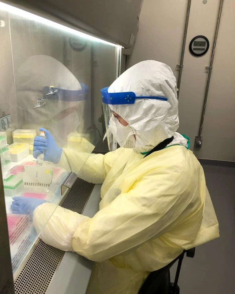 Nathan Marko Markarian gowned in full PPE at a biosafety cabinet inside a BSL-3 containment laboratory