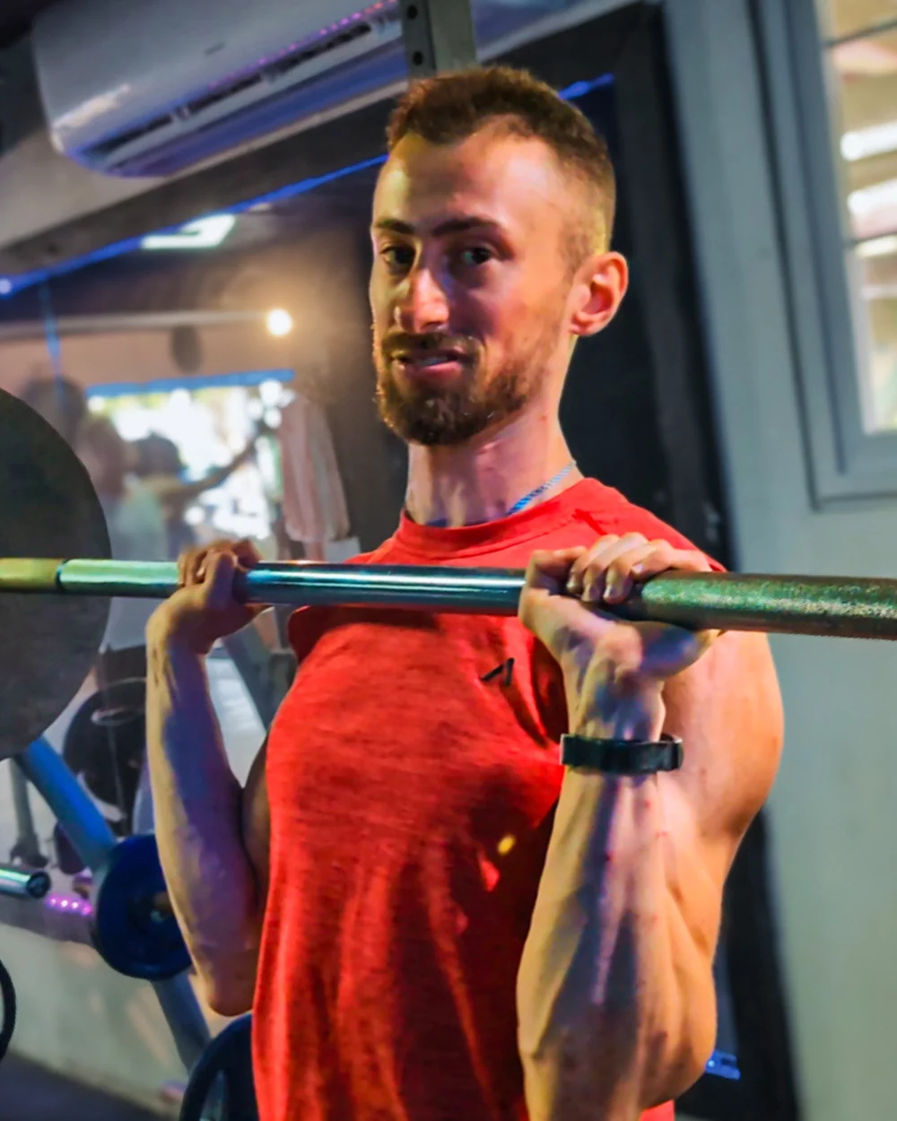 Nathan Marko Markarian mid-set with a loaded barbell in the gym
